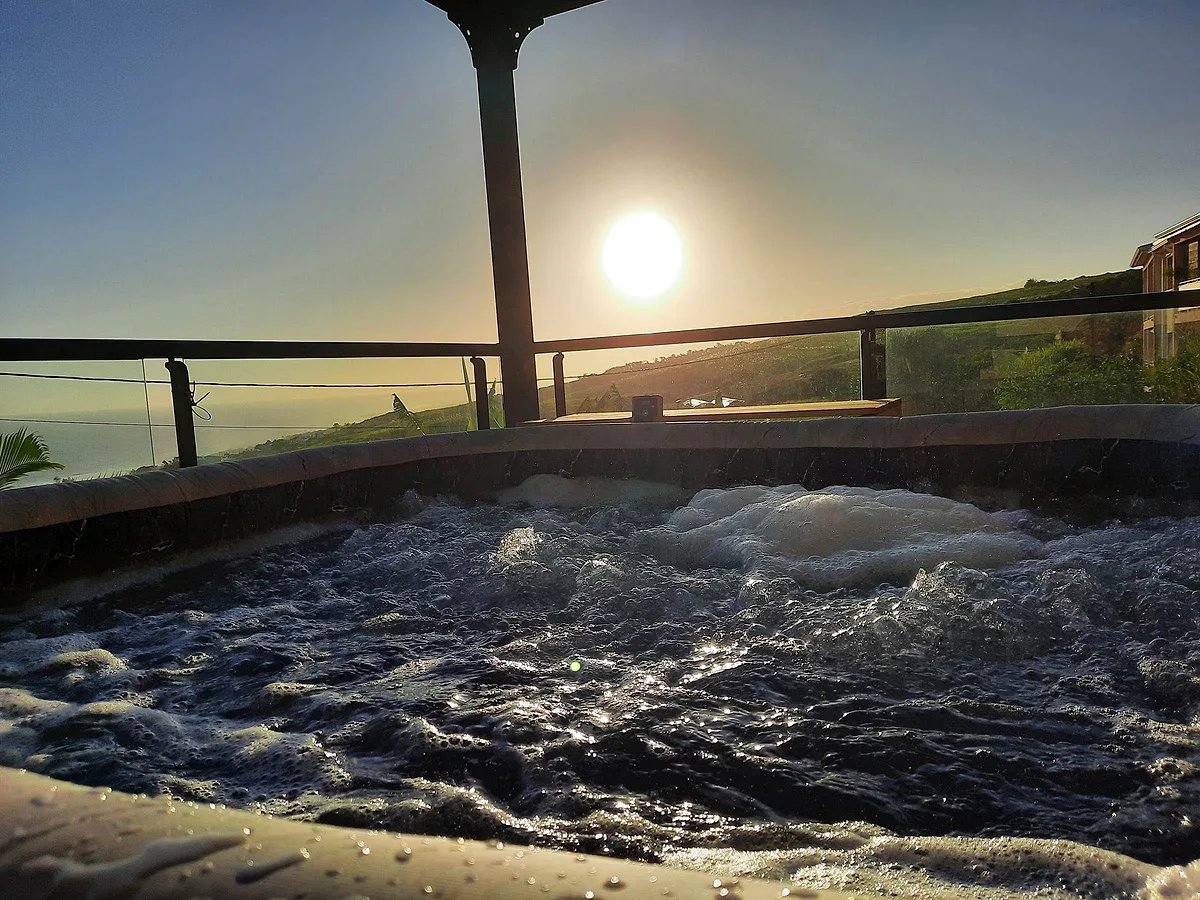 Le spa bouillonnant de la terrasse, le soleil bas sur l'océan