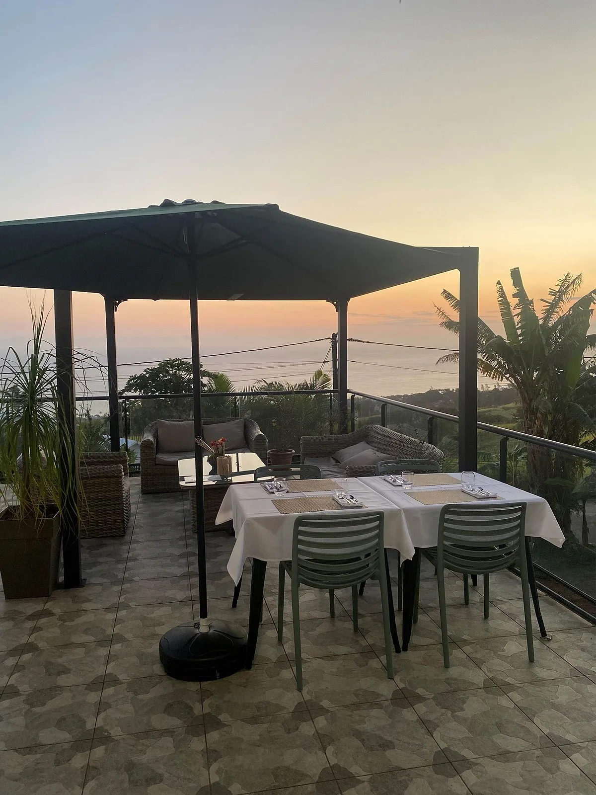 La terrasse de la villa au coucher du soleil, sa table dressée sous la pergola et l'océan